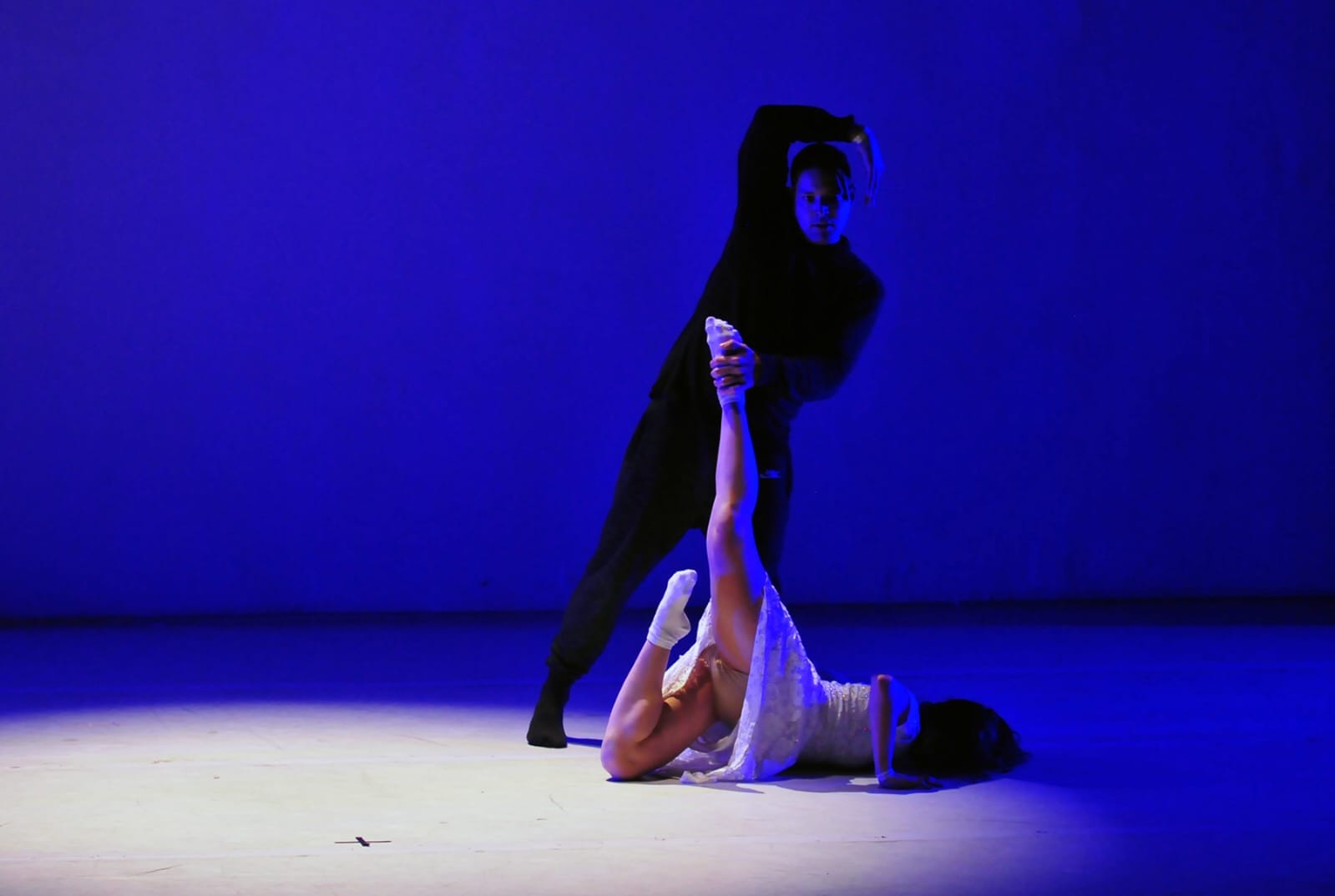 Dupla em apresentação de dança contemporânea sob luz azul